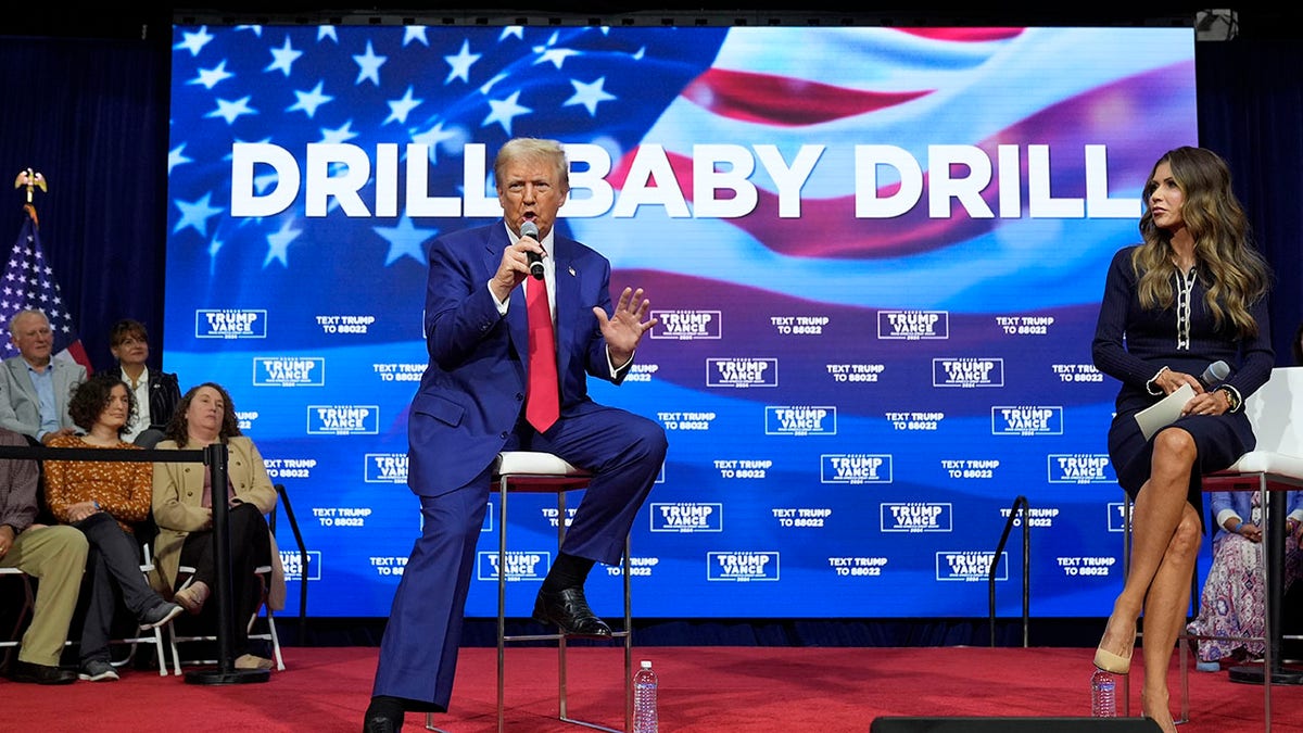 Trump sits in front of baby drilling sign