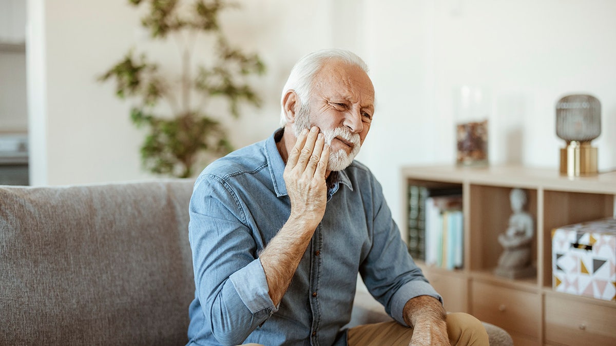 Man who has his face in pain, apparently because of a toothache.