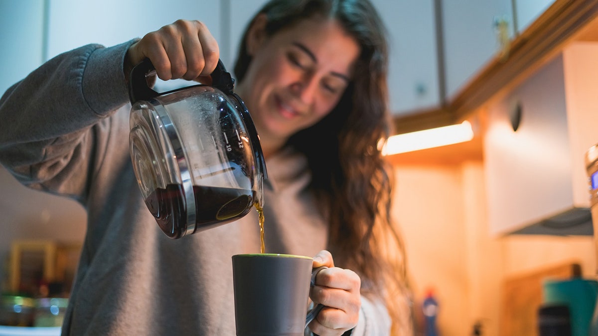 Woman that pours coffee into the cup