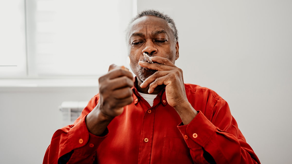 Senior man who has a CBD joint in his mouth and illuminates it.